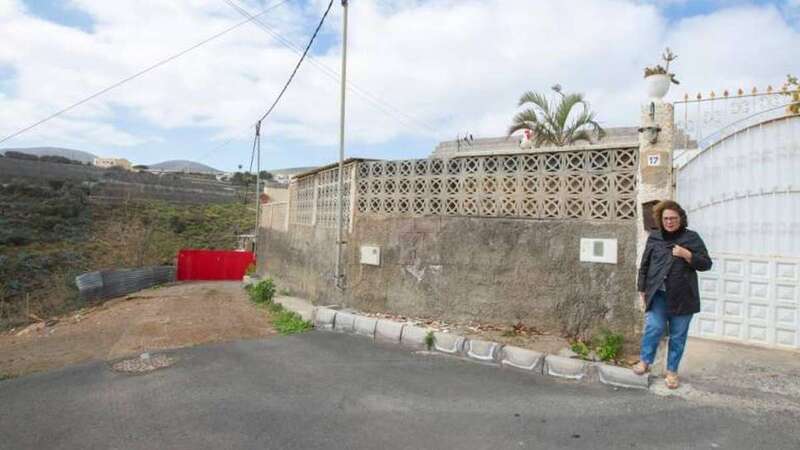 Ángeles Hernández, abuela de la joven enferma, posa delante de su casa. Al fondo, tras la puerta roja, está el ganado que tantos problemas ha generado a su familia  (Foto Borja Suárez/C7)